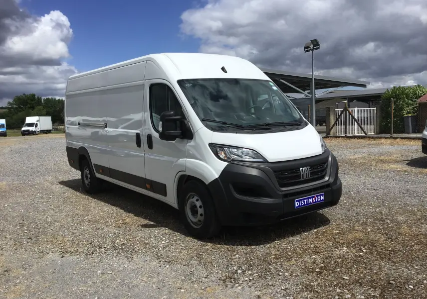 Fourgon blanc Fiat Ducato XLH2 3T5 vu en 3/4 avant droit sur un parking extérieur sous ciel nuageux.