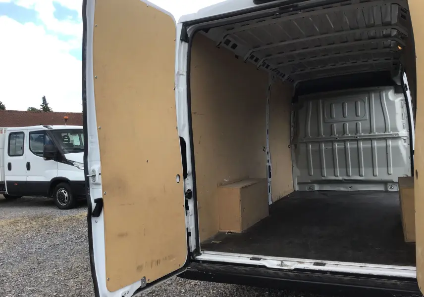 Vue arrière ouverte d'un FIAT Ducato Fourgon blanc 2024, montrant l'intérieur vide avec habillage bois clair.