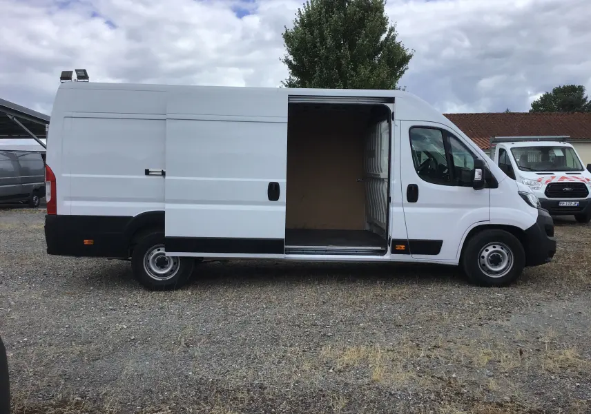 Fiat Ducato Fourgon blanc 2024 vu de profil côté gauche, porte latérale coulissante ouverte dévoilant l’intérieur vide.