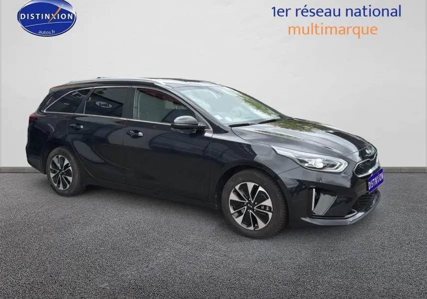 KIA CEE'D SW noir en 3/4 avant droit, avec jantes alu et barres de toit visibles sur fond neutre.