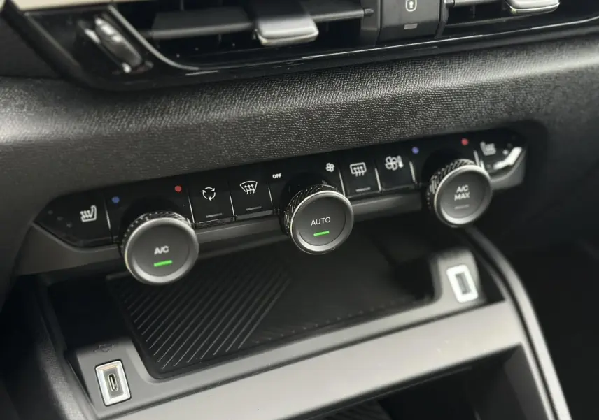 Gros plan sur la console centrale noire du Citroën C4 2025, montrant les commandes de climatisation automatique et sièges chauffants.