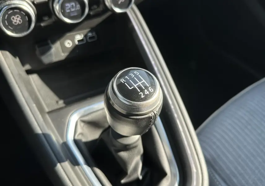 Le levier de vitesses manuel noir de la Renault Clio TCE 90 Techno, vue rapprochée de la console centrale.