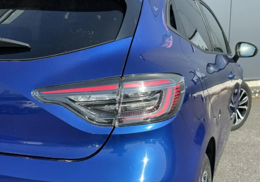 Feu arrière droit en gros plan sur Renault Clio 2025 Bleu Iron, avec reflet et partie latérale visible.