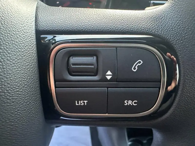 Boutons de commande multifonctions noirs sur le volant du Citroën C3 2023, avec commandes appel et liste.