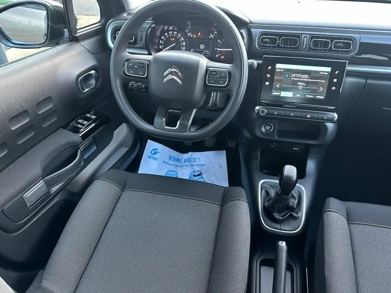 Vue intérieure avant de la Citroën C3 2023 gris, montrant le volant, tableau de bord digital et levier de vitesse manuel.