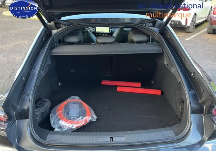 Coffre ouvert vu de l'arrière d'une Peugeot 508 Hybrid 225 GT gris titane avec accessoires de sécurité à l'intérieur.