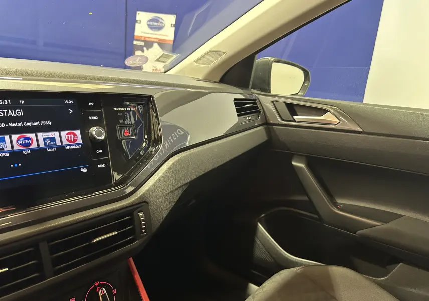 Vue intérieure côté passager de la Volkswagen Polo gris 2018, avec tableau de bord moderne et écran tactile allumé.