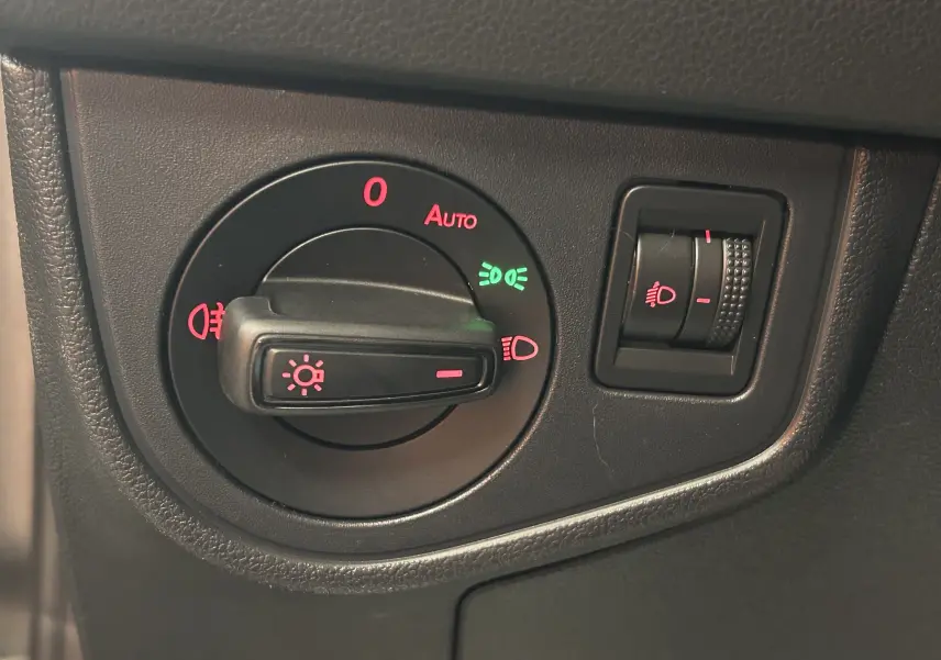 Gros plan sur le bouton de commande des phares avec réglage d'intensité dans l'habitacle d'une Volkswagen Polo gris.