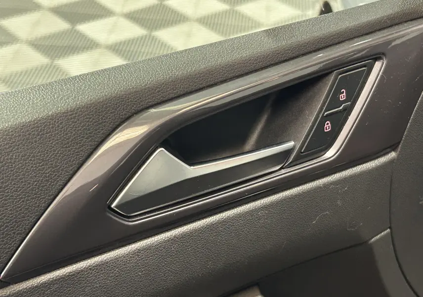 Poignée intérieure de porte côté droit de Volkswagen Polo gris, avec commandes de verrouillage centralisé.