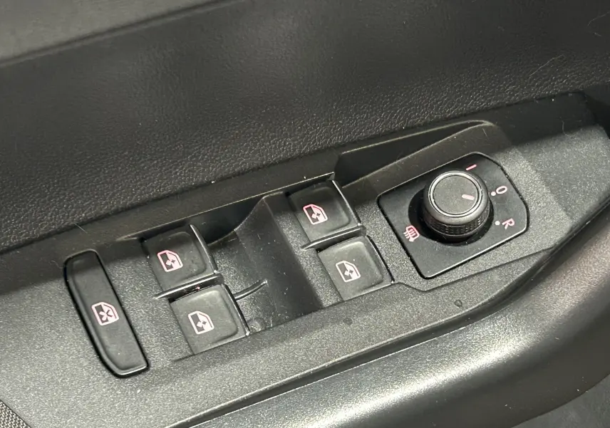 Gros plan sur les commandes électriques des vitres et réglage des rétroviseurs côté conducteur d'une Volkswagen Polo gris 2018.