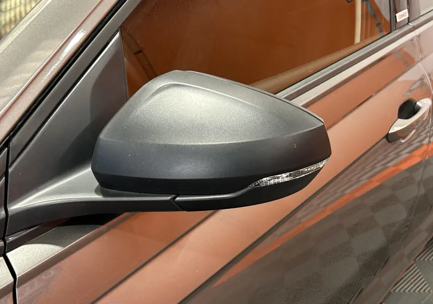 Gros plan sur le rétroviseur noir mat côté gauche d'une Volkswagen Polo gris métallisé, avec clignotant intégré.