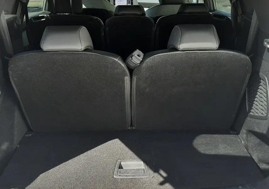Vue arrière du coffre ouvert du Peugeot 5008 blanc Okenite, montrant les sièges arrière en position verticale.