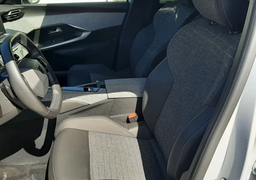 Vue intérieure côté conducteur du Peugeot 5008 Hybrid 2025 blanc Okenite, sièges tissu et cuir noir avec console centrale.