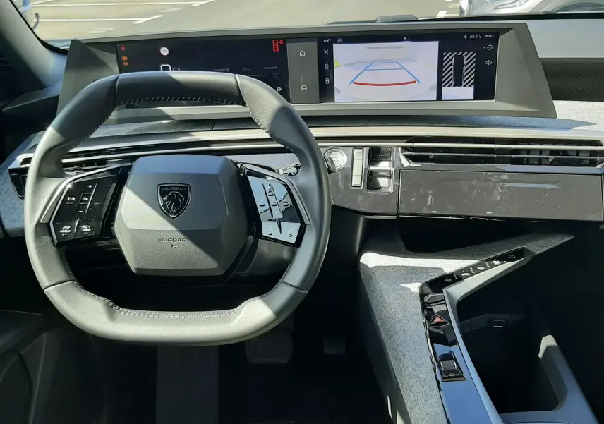Vue intérieure du tableau de bord et volant du Peugeot 5008 Hybrid 2025, avec écran tactile et affichage caméra de recul.
