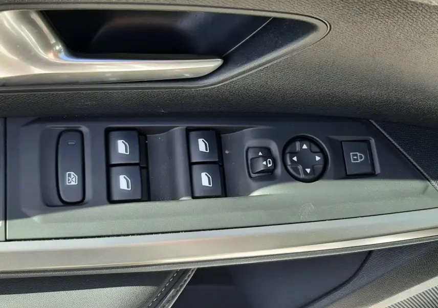Gros plan sur les commandes de lève-vitres et rétroviseurs côté gauche d’une Peugeot 5008 Hybrid blanche.