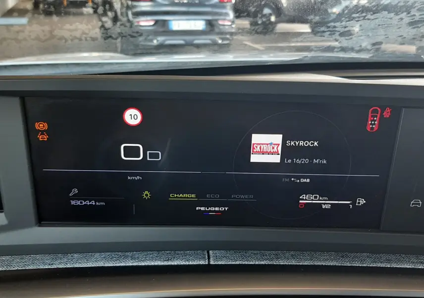 Vue intérieure du tableau de bord numérique du Peugeot 5008 Hybrid 2025, affichant la radio et l'autonomie restante.