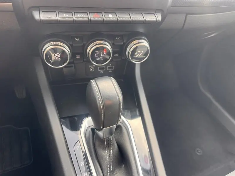 Gros plan sur la console centrale noire du Renault Arkana blanc perle 2023, avec levier de vitesse automatique et commandes climatiques.