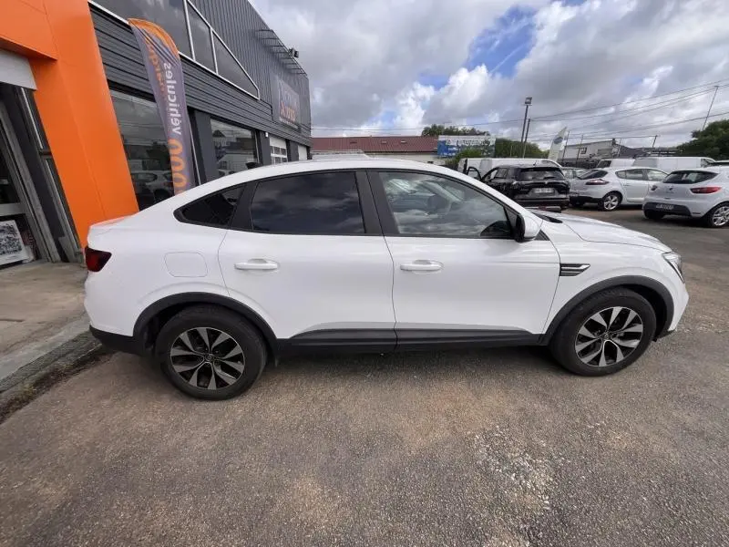 Profil côté gauche du Renault Arkana blanc perle 2023 avec jantes alliage noires et vitres surteintées.