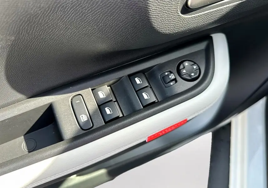 Gros plan sur la commande des vitres électriques côté conducteur d'une Citroën C3 Aircross blanche, avec bouton de réglage des rétroviseurs.
