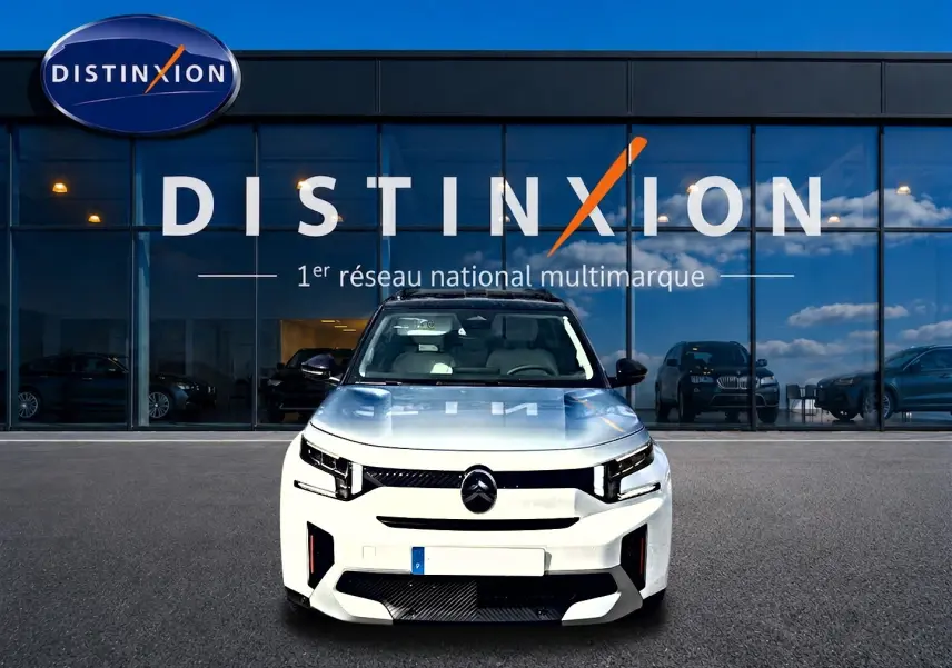 Vue avant d'un Citroën C3 Aircross blanc 2026 avec toit noir, devant une vitrine Distinxion.