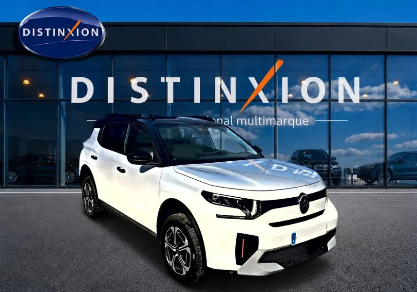 Vue 3/4 avant droite d'un Citroën C3 Aircross blanc avec toit noir et jantes alu devant une vitrine Distinxion.