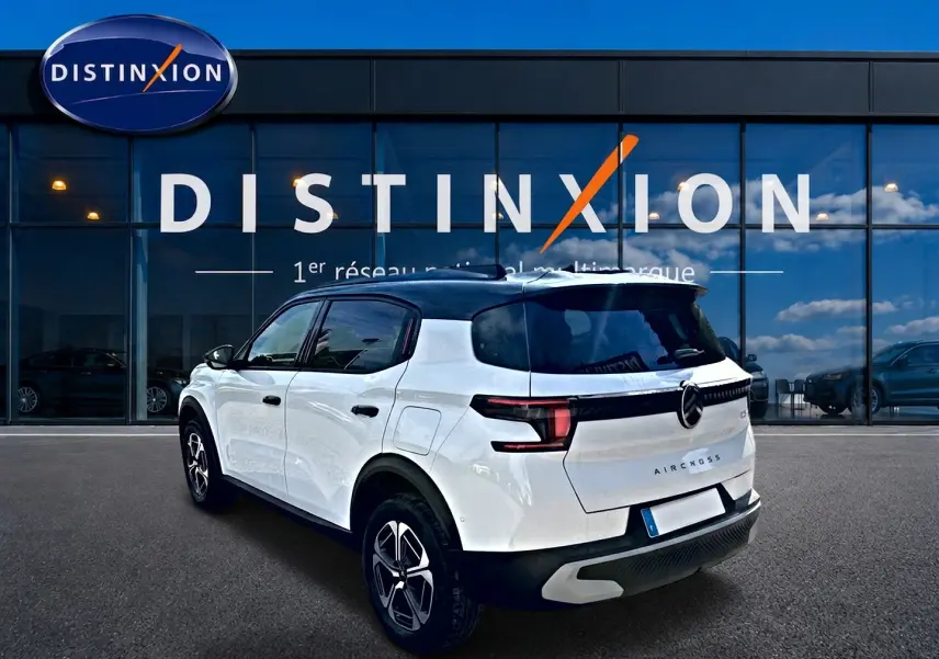Vue 3/4 arrière droite d'un Citroën C3 Aircross blanc avec toit noir, jantes alu et feux arrière LED noirs.