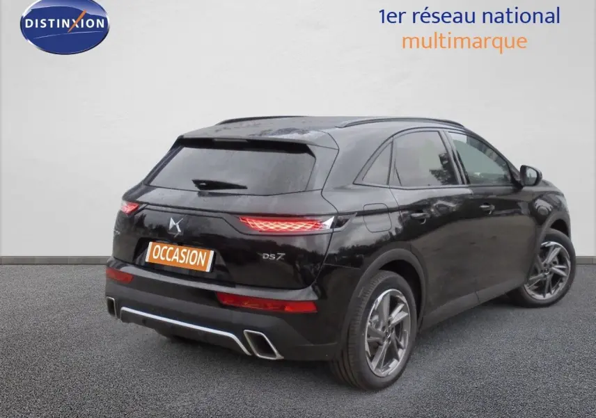 Vue 3/4 arrière droite d’un DS7 Crossback noir perle métal avec feux arrière allumés sur fond neutre.