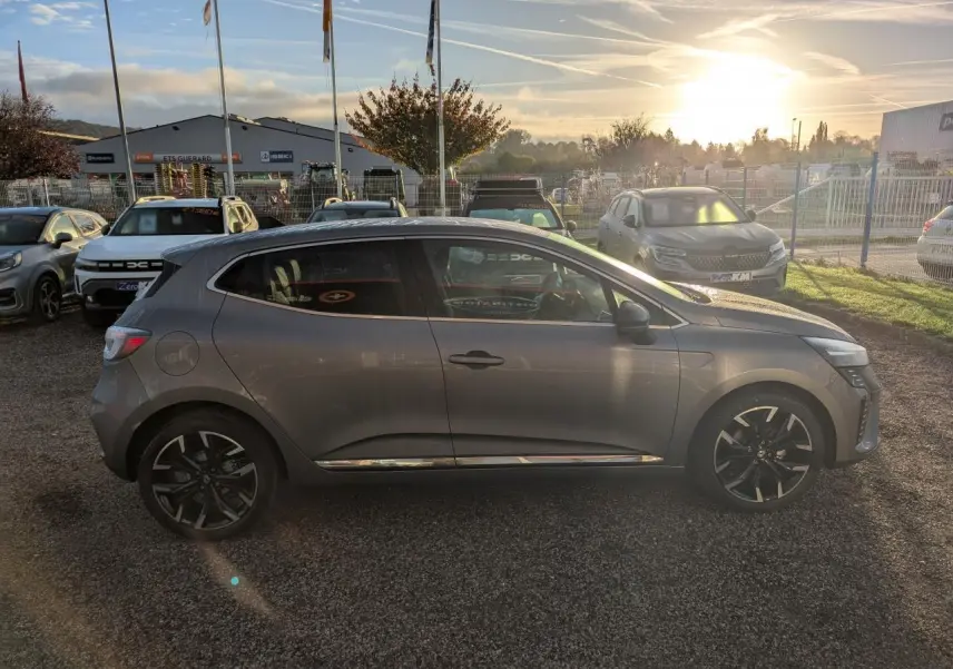 Profil côté droit d'une Renault Clio 2025 gris schiste avec jantes alliage noir monastella et contour de vitres chromé.