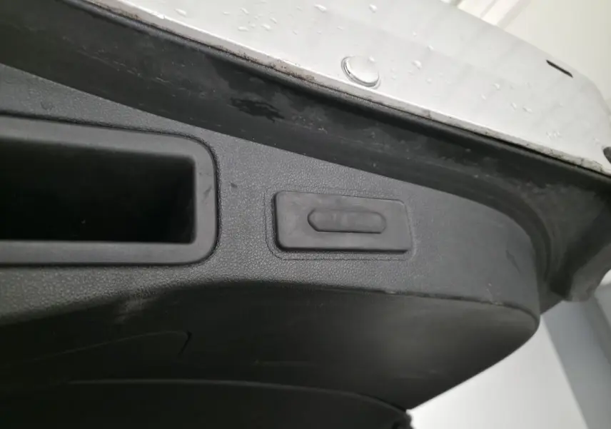 Gros plan sur le bouton d'ouverture mains-libres du hayon motorisé de la Renault Talisman Estate gris.