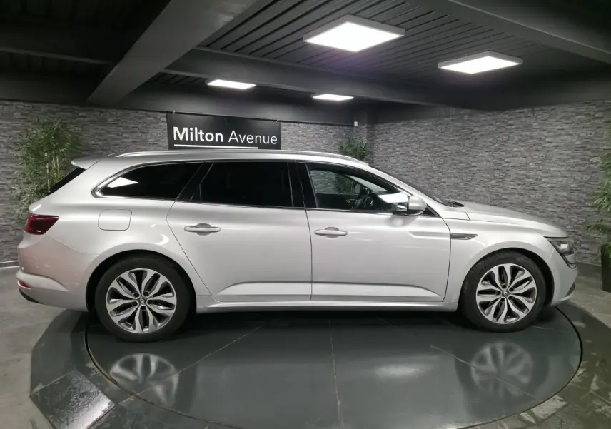 Profil droit d'une Renault Talisman Estate gris platine 2018 avec jantes alliage et vitres surteintées en showroom.