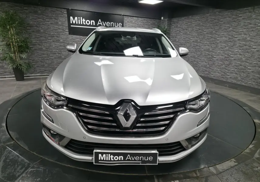 Vue frontale d'une Renault Talisman Estate gris platine avec calandre noire et logo Renault proéminent.