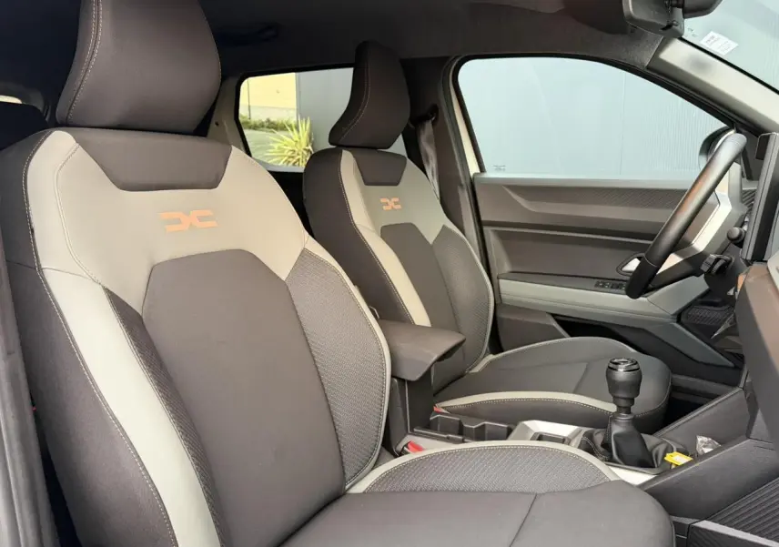 Vue intérieure côté droit montrant les sièges TEP MicroCloud beige et brun cuivré du Dacia Duster 2025 avec levier de vitesses manuel.
