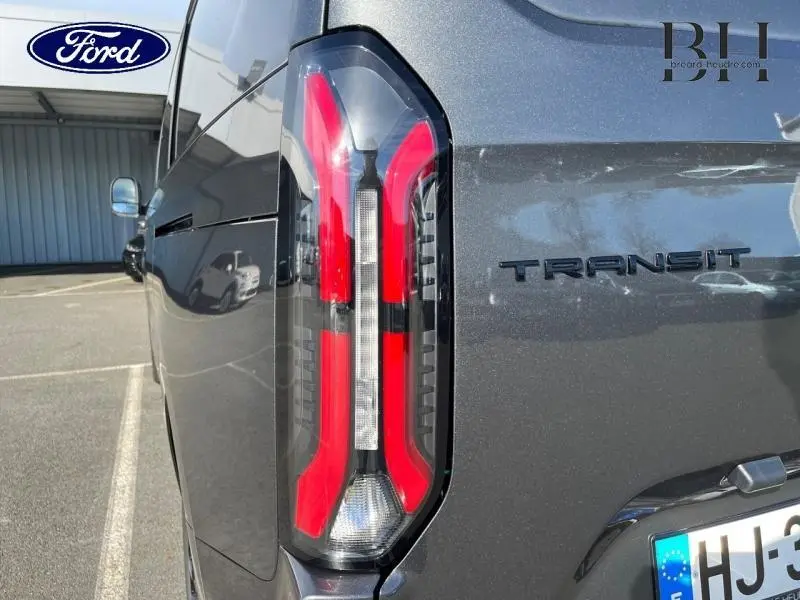 Vue arrière côté gauche du Ford Transit Custom gris métallisé, mettant en valeur le feu arrière LED et le logo TRANSIT.