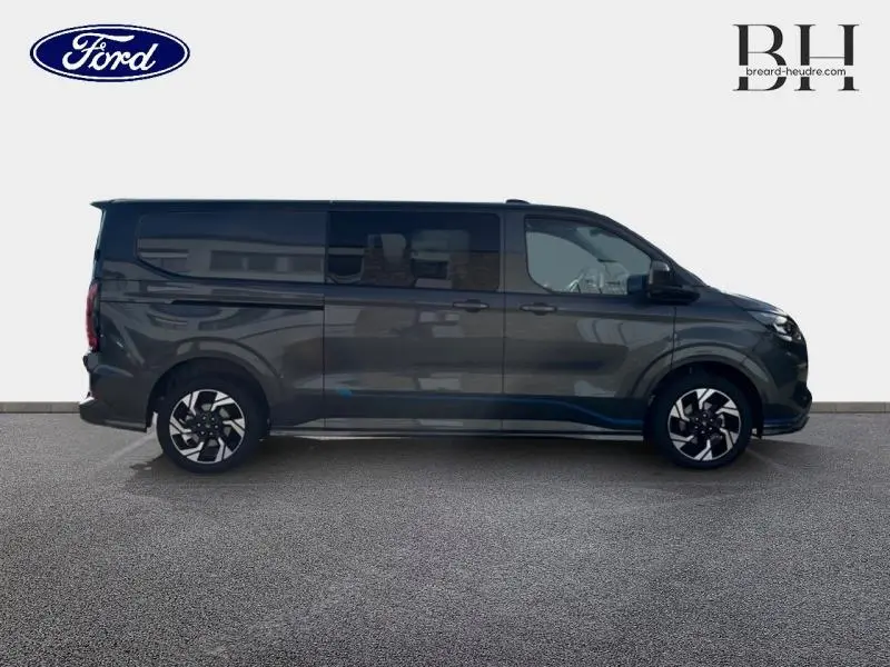 Profil droit du Ford Transit Custom Fourgon 2026 gris Magnetic métallisé avec jantes alu et vitres arrière surteintées.