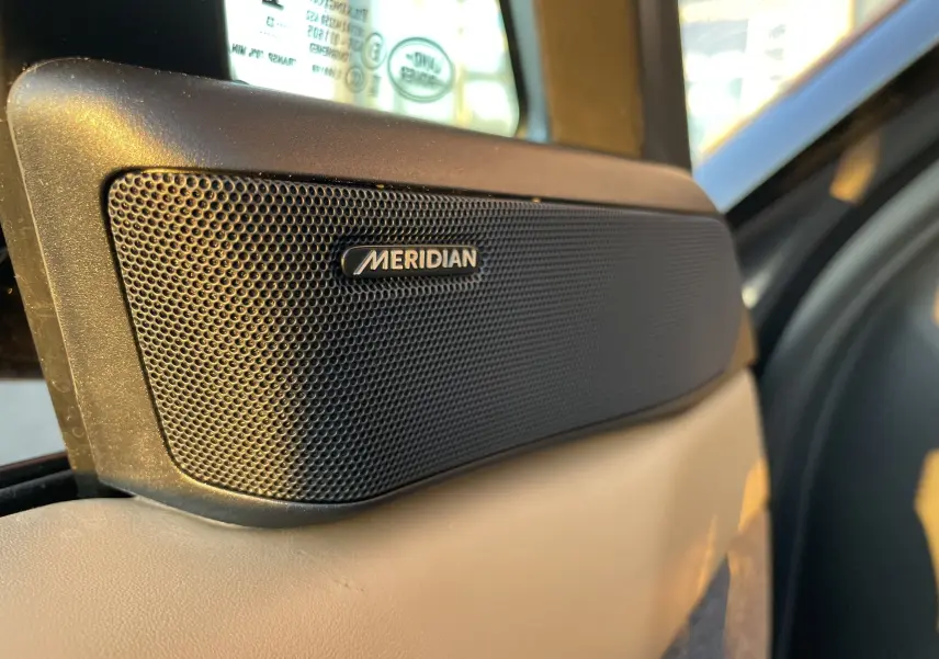 Gros plan sur l'enceinte Meridian intégrée à la porte intérieure beige du Range Rover Sport P440 HSE R-Dynamic 2023.