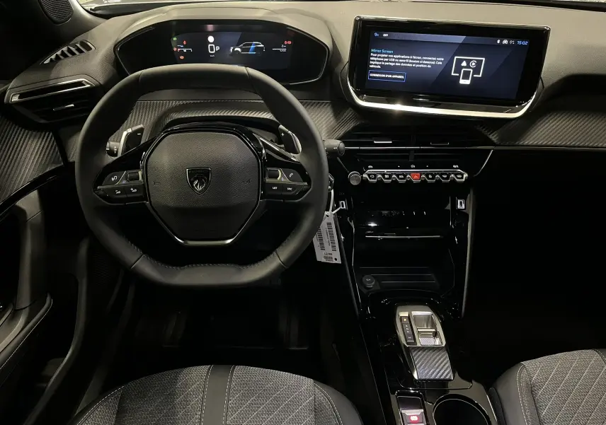 Vue intérieure frontale du tableau de bord et volant noir du Peugeot 2008 1.2 Hybrid 145ch Allure, avec écran tactile et finitions carbone.