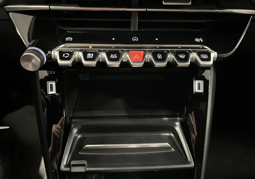 Vue rapprochée de la console centrale noire brillante du Peugeot 2008 1.2 Hybrid 145ch avec boutons de commande et ports USB.