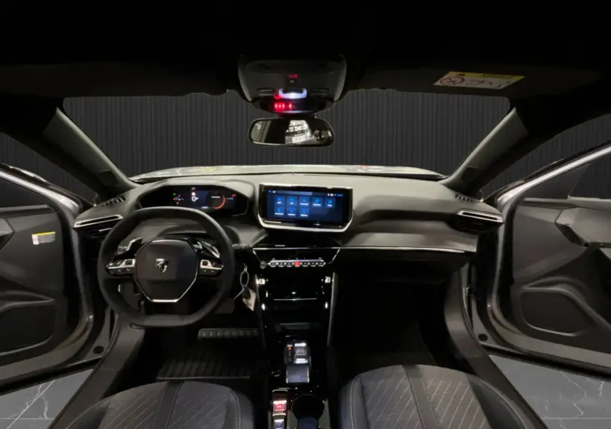 Vue intérieure avant du Peugeot 2008 gris Artense avec tableau de bord numérique et écran tactile central allumé, portes ouvertes.