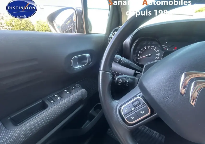 Vue intérieure côté conducteur du Citroën C3 Aircross gris foncé, avec volant multifonction et commandes sur portière.