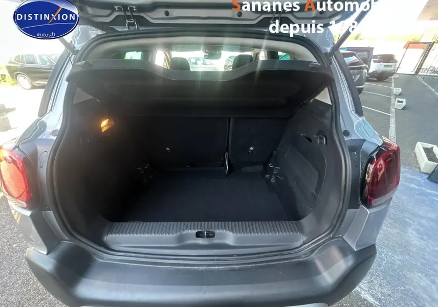 Coffre ouvert vu de l'arrière d'un Citroën C3 Aircross gris foncé, montrant l'espace de chargement vide.