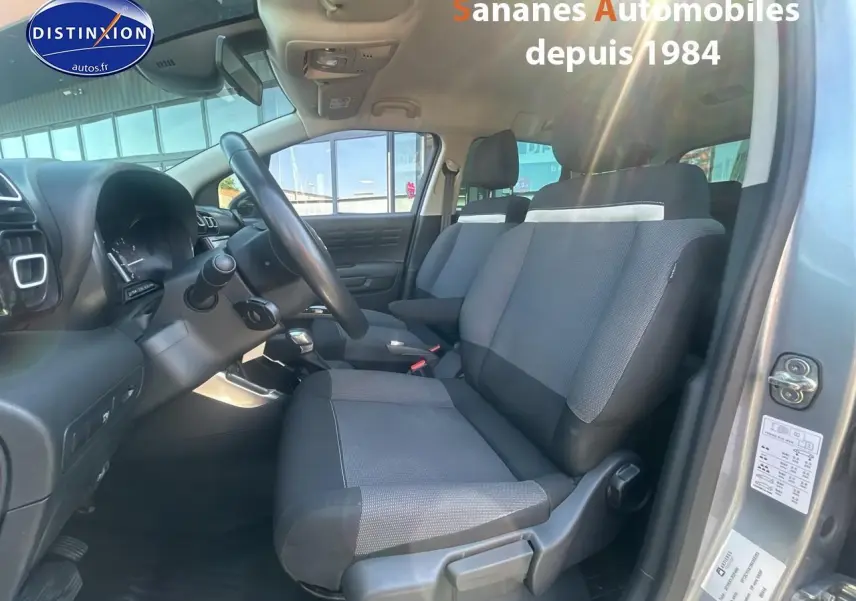 Vue intérieure côté conducteur du Citroën C3 Aircross gris foncé, mettant en valeur les sièges tissu Mica Grey et le volant.