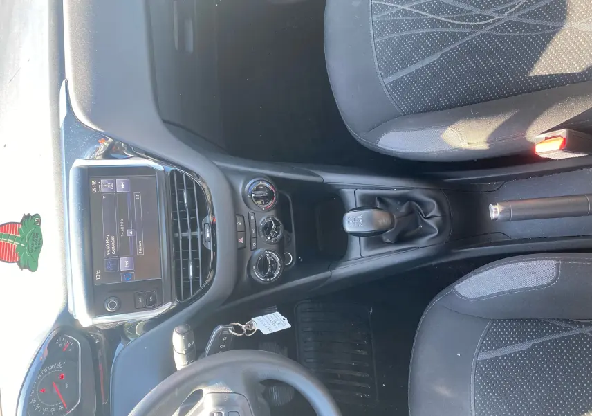 Vue intérieure du poste de conduite d'une Peugeot 208 blanche 2014, avec tableau de bord, volant, et levier de vitesses manuel.