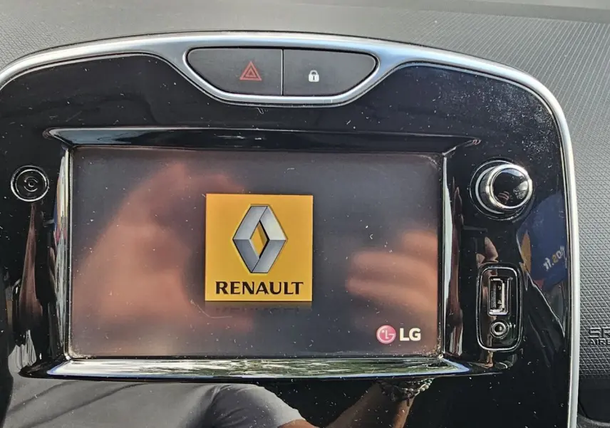 Écran tactile central LG affichant le logo Renault dans l'habitacle d'une Clio IV gris 2015, finition Zen.