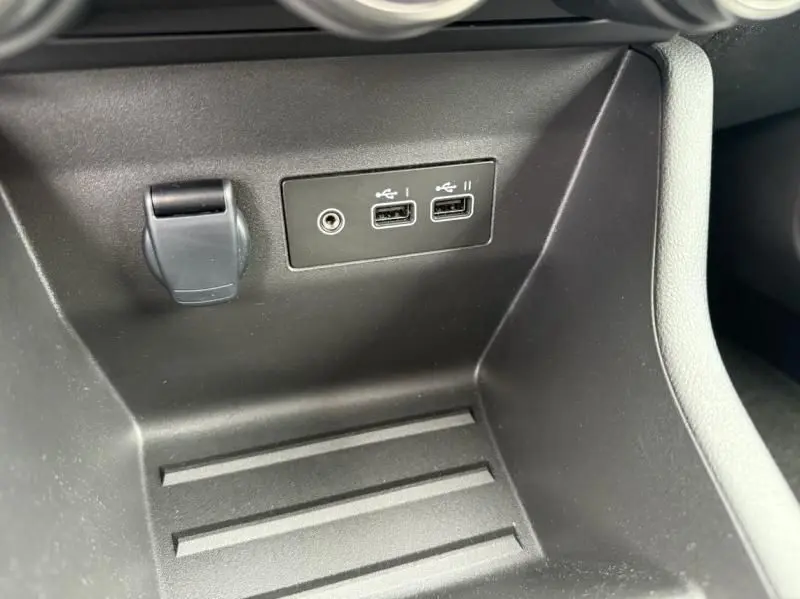 Prise USB et port auxiliaire en gros plan dans la console centrale noire d'une Renault Clio V orange SCE 65 Evolution 2025.