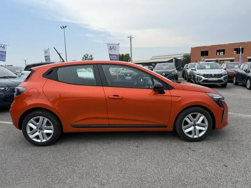 Profil côté gauche d'une Renault Clio V orange 2025 SCE 65 Evolution, avec jantes argentées et lignes dynamiques visibles.