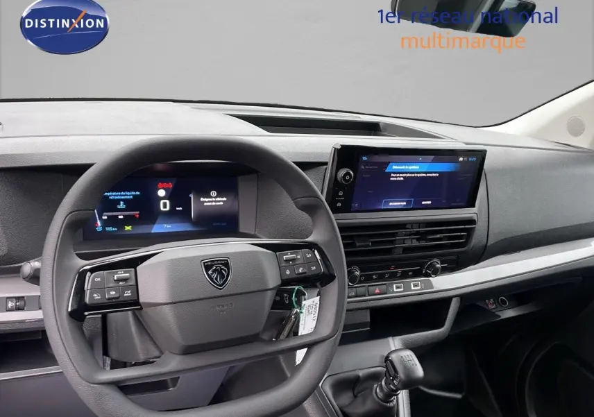 Intérieur du Peugeot Expert Fourgon 2025 vu de face, volant multifonction et écran tactile central sur tableau de bord gris.