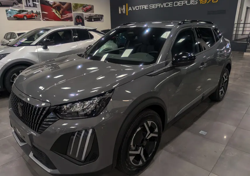 Peugeot 2008 Hybrid 145 e-DCS6 Allure gris Sélénium en 3/4 avant droit, avec jantes bicolores et feux LED distinctifs.