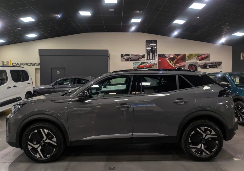 Profil côté gauche du Peugeot 2008 Hybrid 145 e-DCS6 Allure gris Sélénium avec jantes biton en showroom.