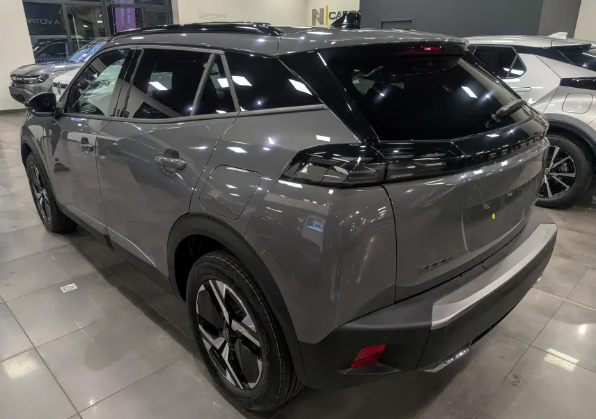 Peugeot 2008 Hybrid 145 gris Sélénium vue 3/4 arrière droit avec toit noir brillant en showroom.
