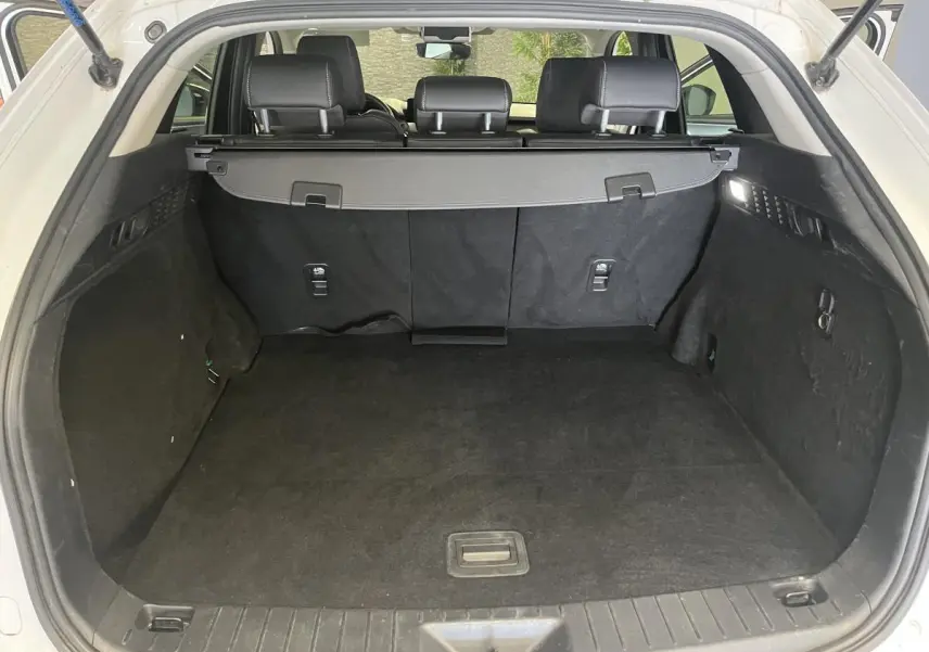 Coffre ouvert du Mazda CX-60 blanc 2023, vue arrière montrant l'espace de chargement et la plage arrière noire.